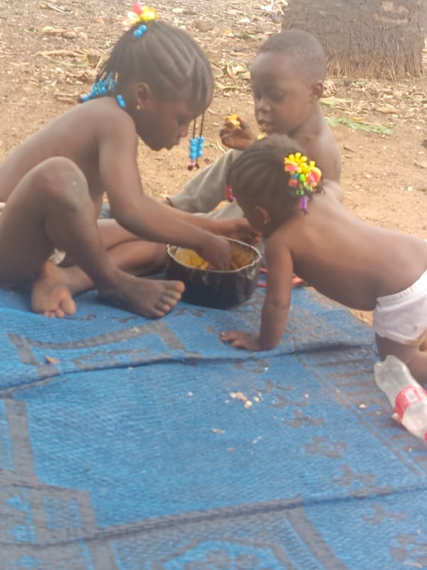 Children share outdoor meal on mat in Akwanga, Nigeria