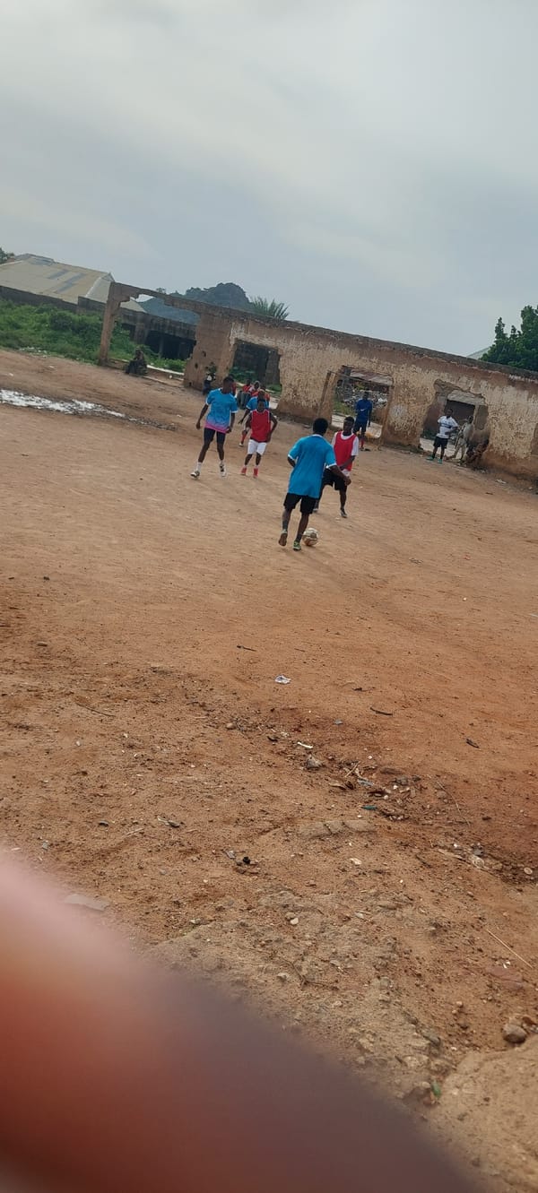Informal soccer game on a dirt field in Bukuru, Nigeria