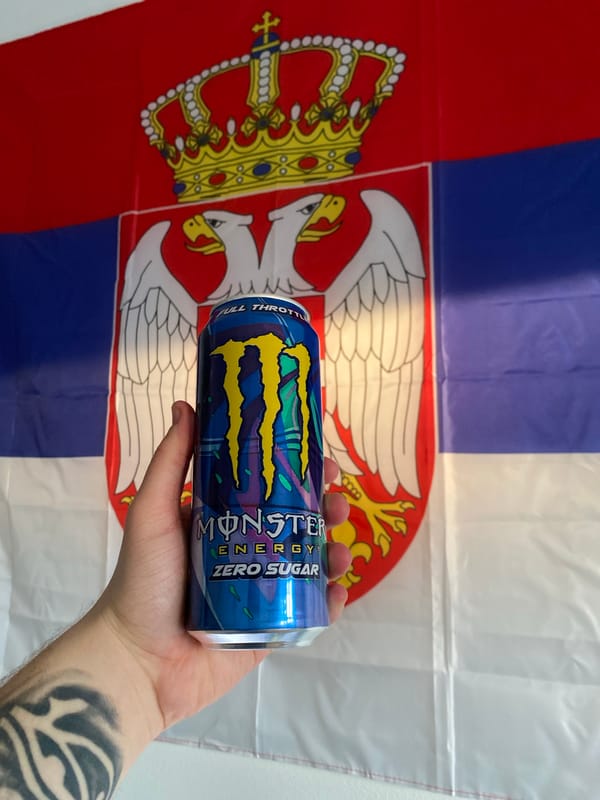 Energy drink held with Serbian flag backdrop in Subotica