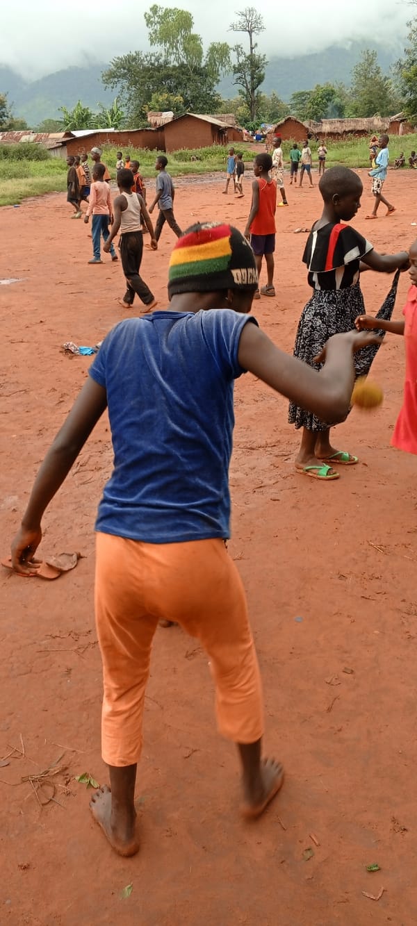 Adult supervises children's outdoor activities in rural Congo villages