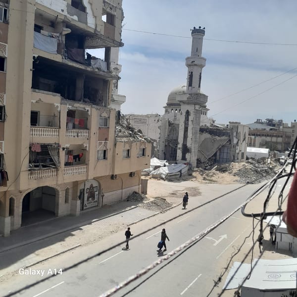 Urban street shows widespread building damage including mosque