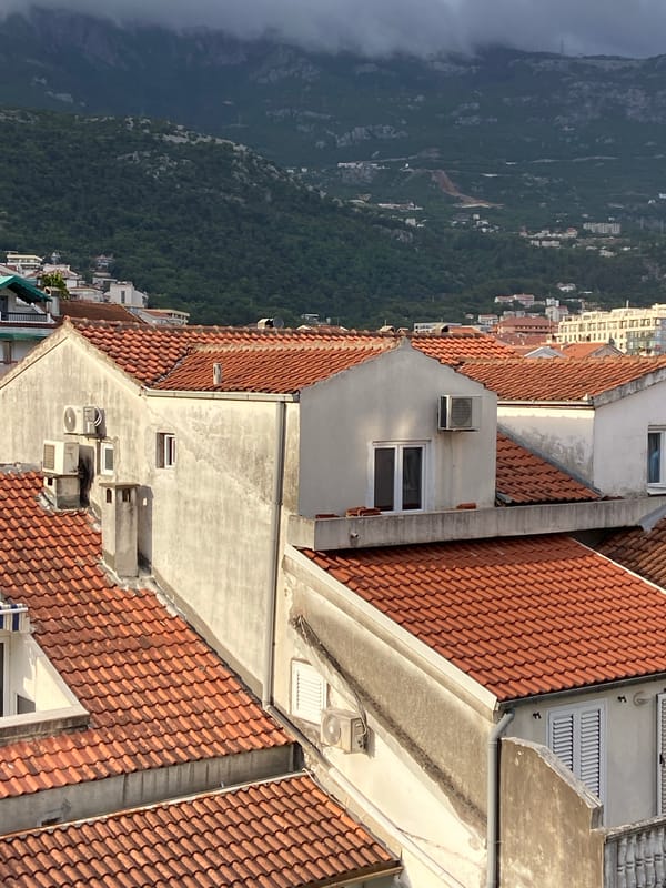Aerial views document Budva's urban landscape under cloudy skies