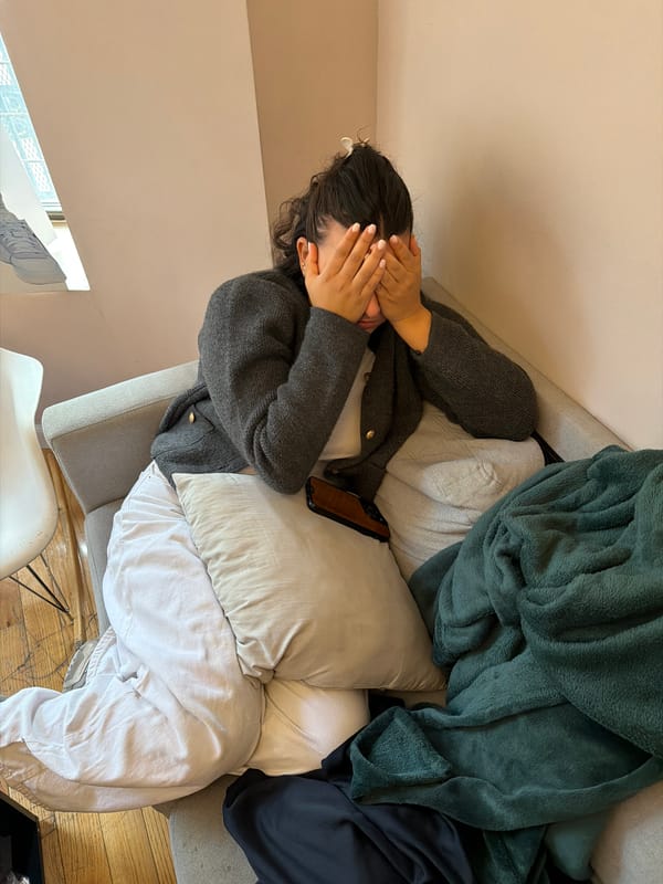 Woman lies face-down on sofa covering face in New York