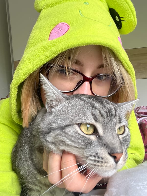 Person in frog onesie holds cat in Boreti