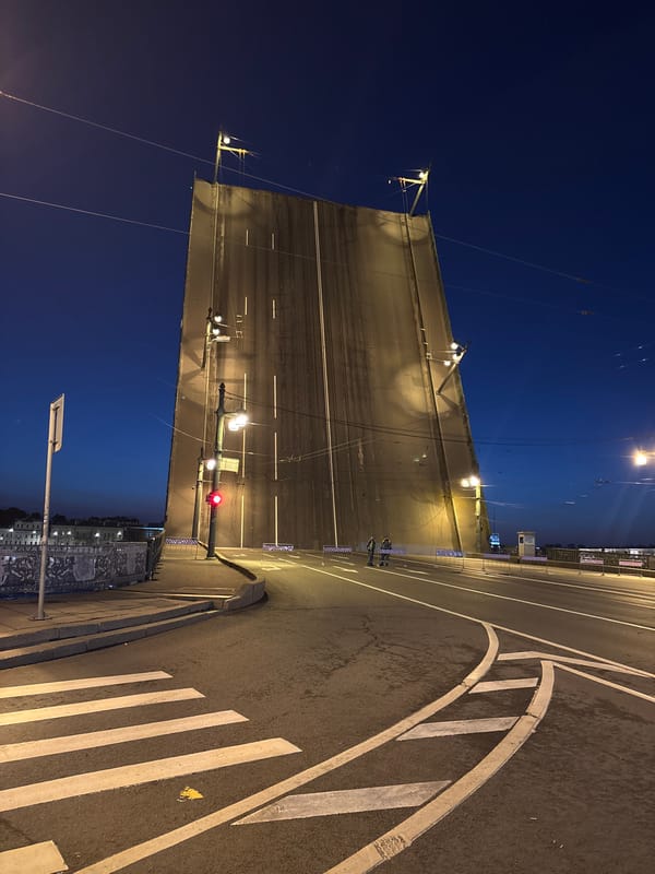 Drawbridge raised at night, illuminated by streetlights over water