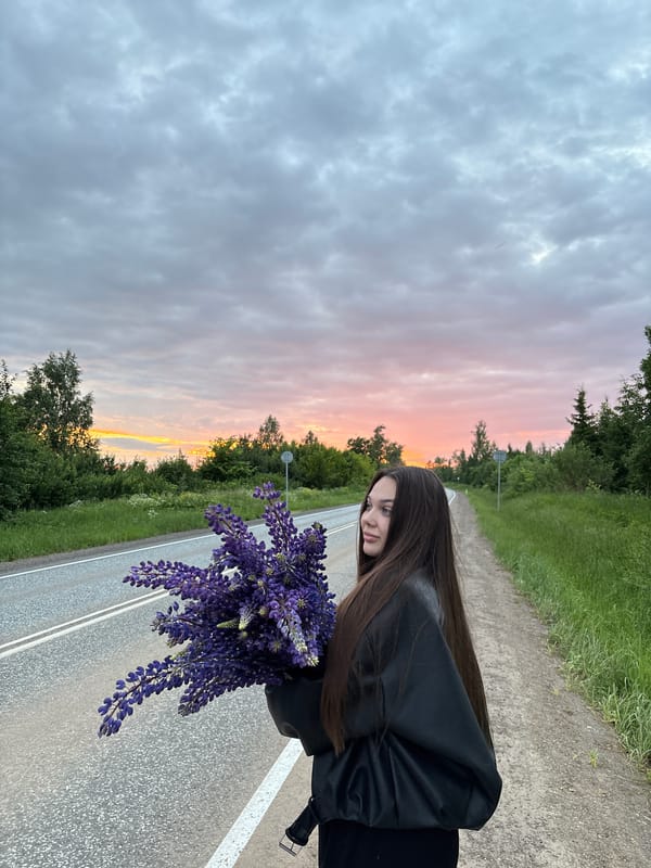 Woman holds purple lupine bouquet on roadside in Garevaya