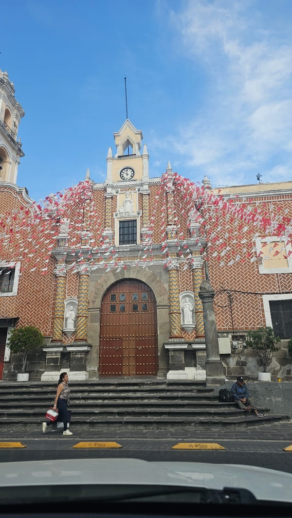 Historic Puebla church adorned with ceremonial red and white flags