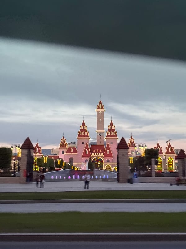 Urban evening walkthrough: streets, towers, and a lit-up theme park