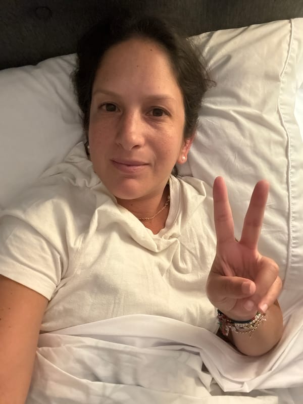Woman makes peace sign gesture in bed in San Isidro