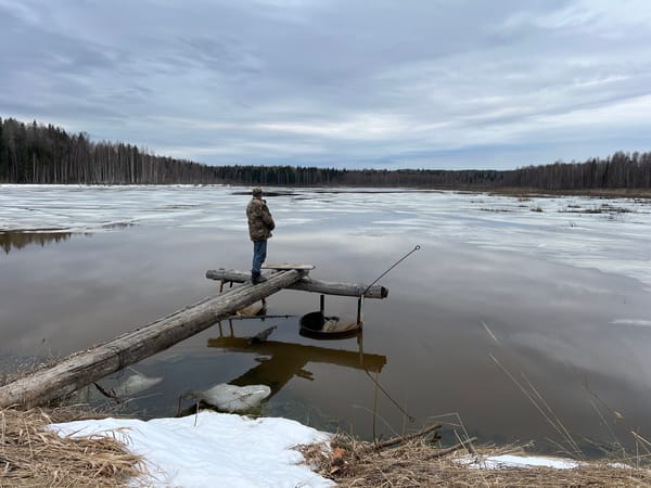 Man stands on wooden pier in partially frozen waters, Posha