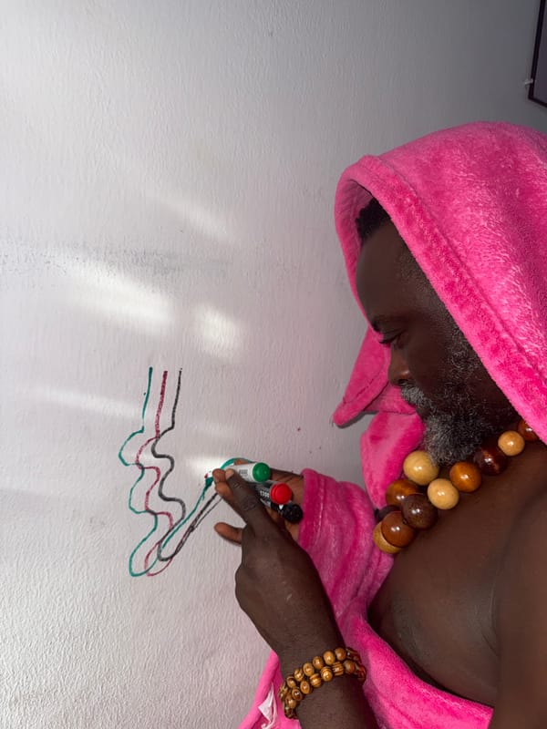 Person in pink robe creates wall art in Ado