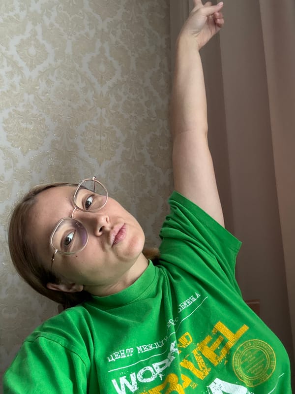 Looking up at a high-angle camera, arm raised, indoors