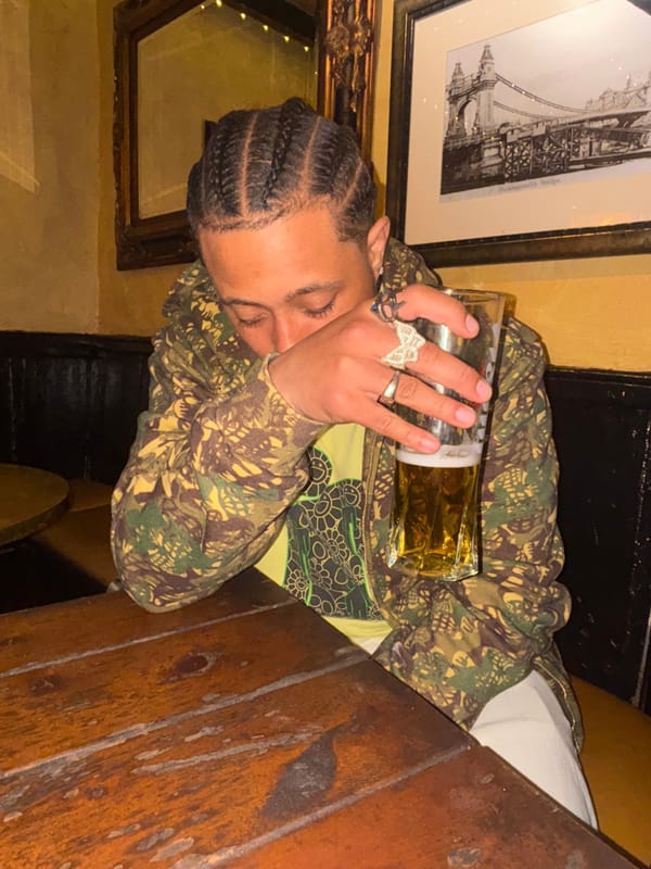 Man with cornrows enjoys pint in London indoor venue