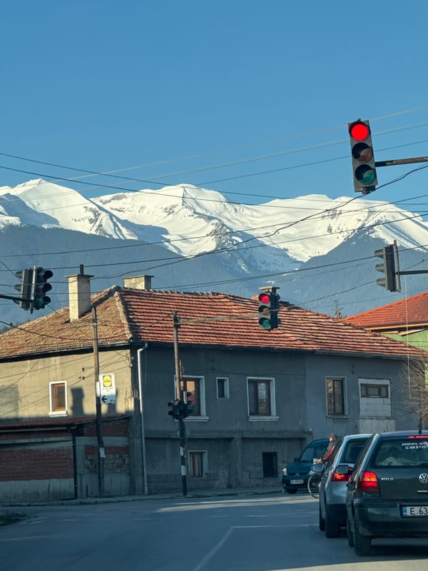 Morning street view captures snowy mountains behind Razlog traffic lights