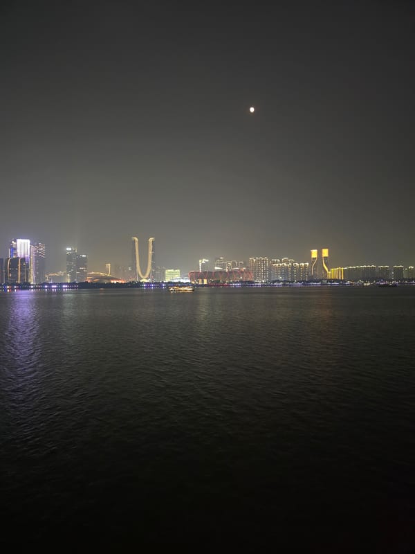 Shangcheng District skyline glowing across the water at night