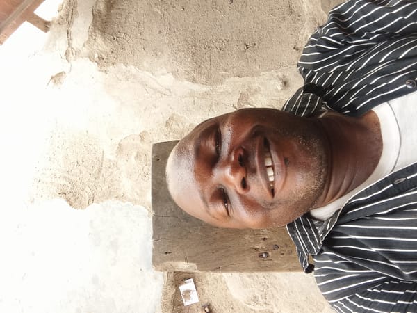 Man sits smiling on wooden plank outdoors