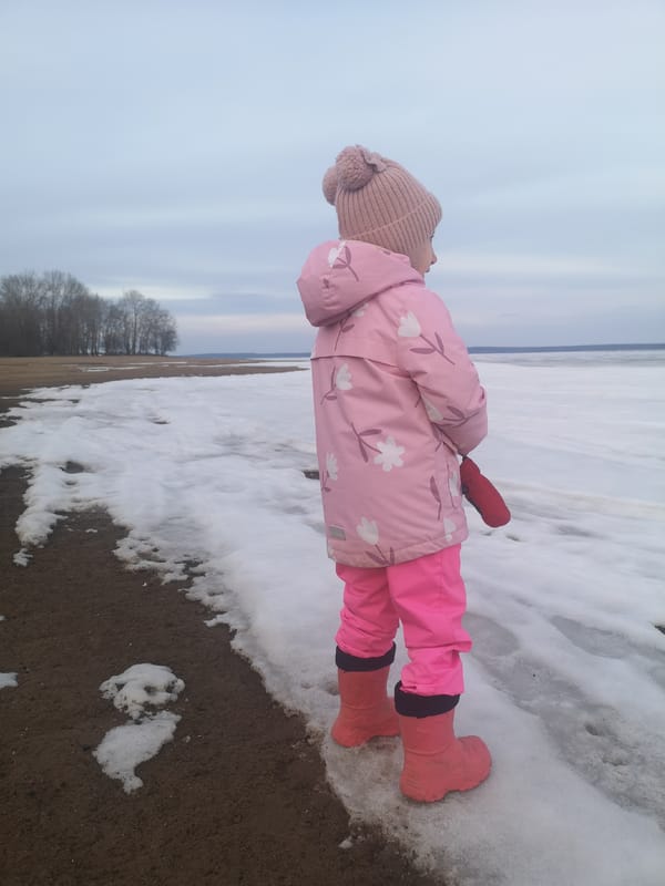 Mother and child explore frozen Russian shoreline in spring