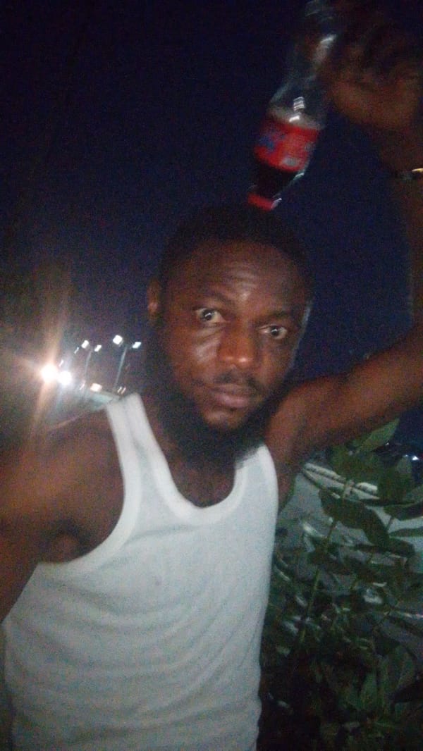 Man poses with beverages during evening photo session in Lokoja