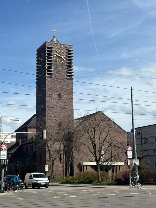 Munich church tower observed under cloudy skies with contrails