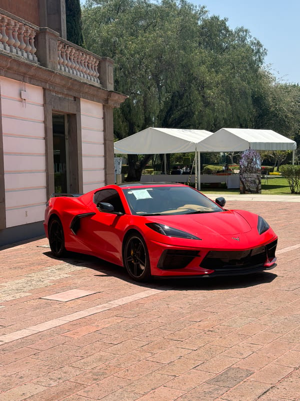 Red sports car spotted parked near building with tents