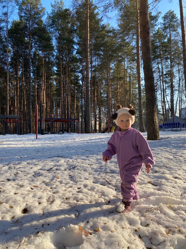 Child plays in snow wearing panda hat in Russian woods