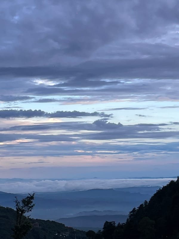 Bhagsu hillside town under moody mountain cloudscape