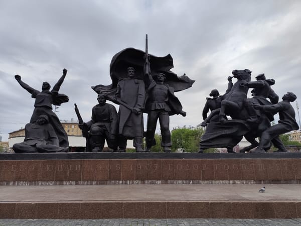 Bronze monument with multiple figures observed under grey skies