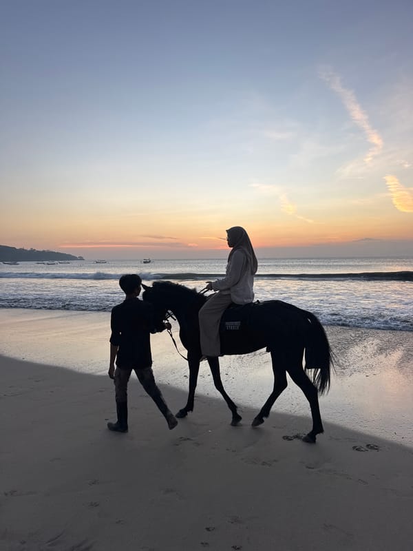 Sunset beach dinner event, horses, and evening crowds at Kuta