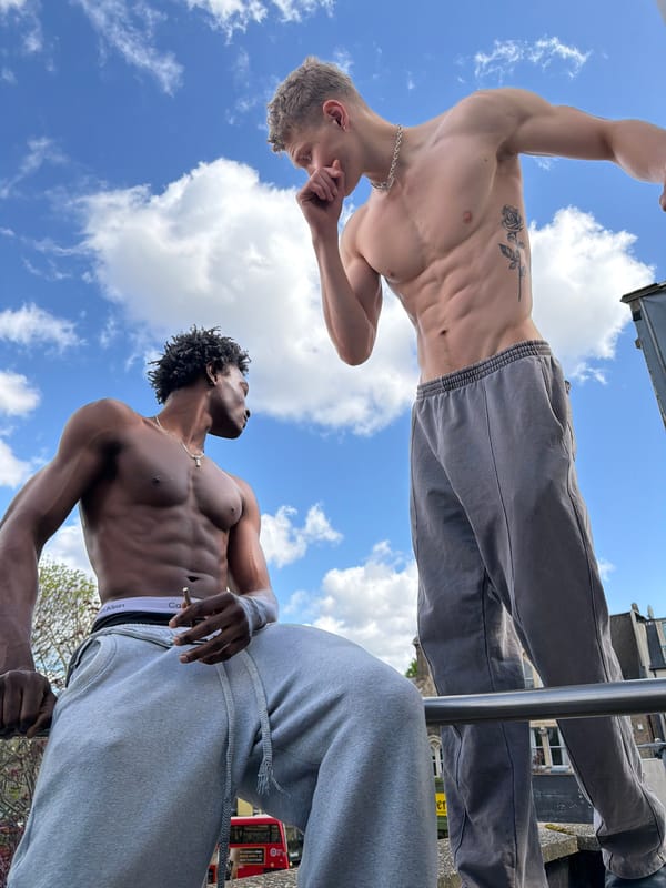 Two men pose shirtless on London balcony, cat photographed nearby