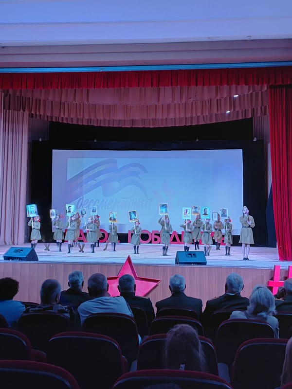 Children perform commemorative theater presentation with framed pictures