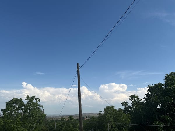 Utility pole stands against blue sky with white clouds