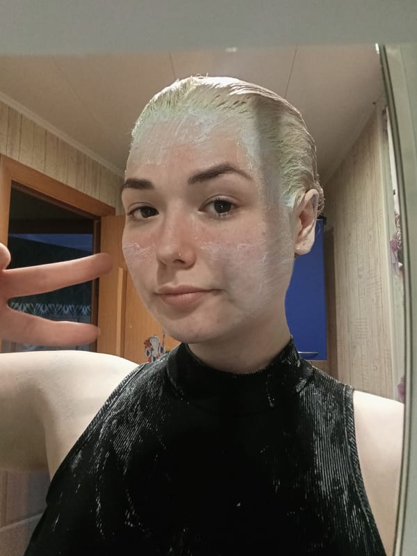 Young person takes mirror selfie indoors with neutral expression
