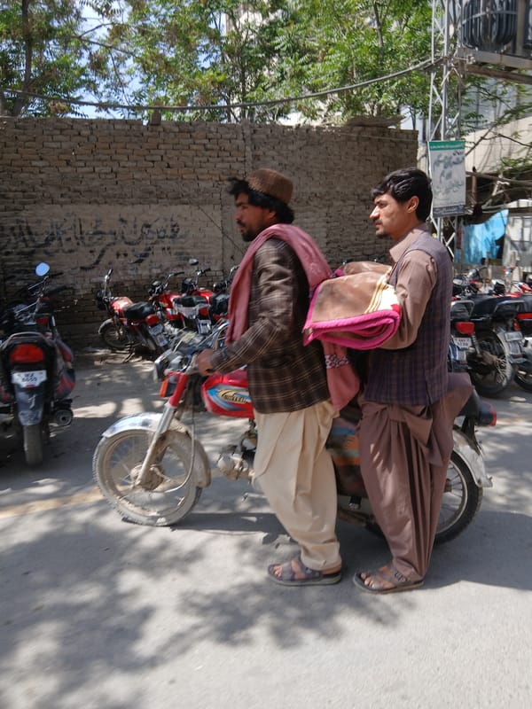 Two men ride motorcycle through Quetta streets