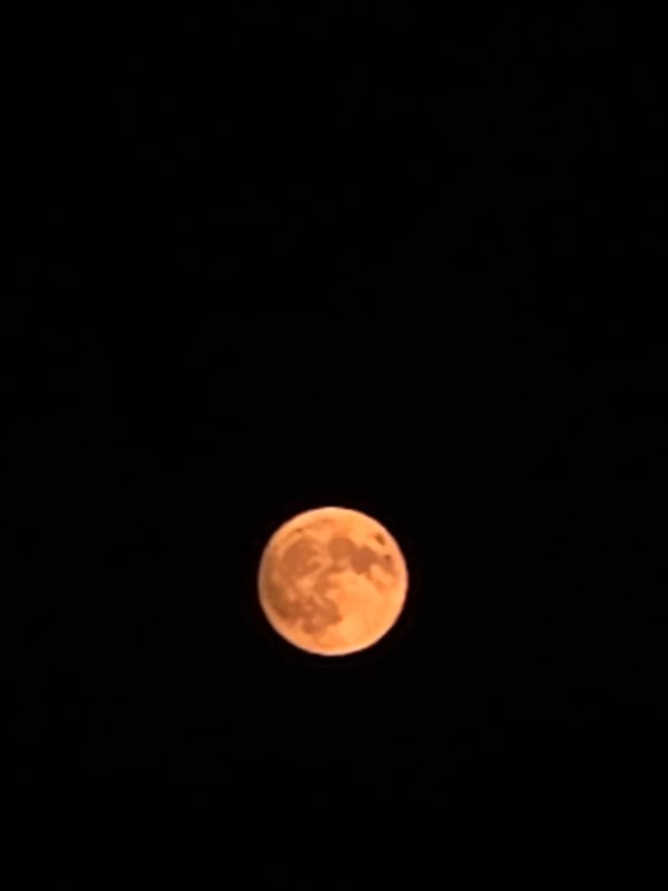Orange full moon rises over Fumane on a clear July night
