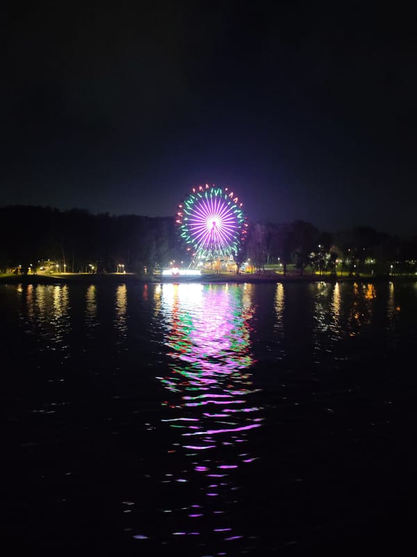 Cherepovets waterfront at night: bridge, Ferris wheel, riverside café