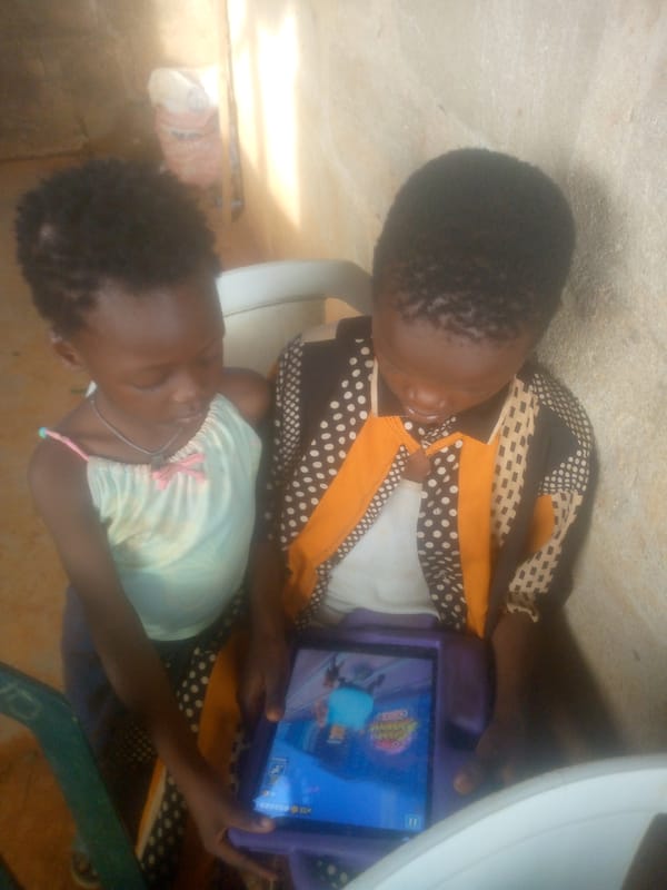 Children share tablet time on chair in Ikorodu