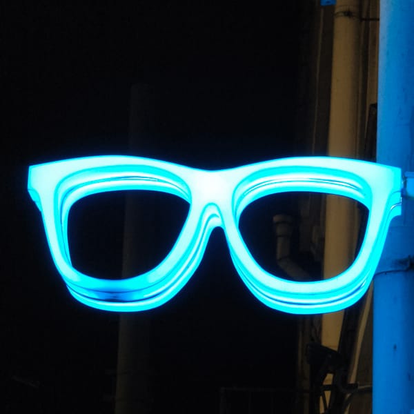 Neon eyeglasses sign glows in evening Hrodna street