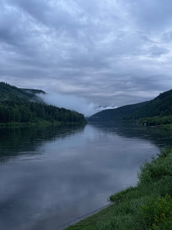 Misty river winds through forested hills in rural Siberia