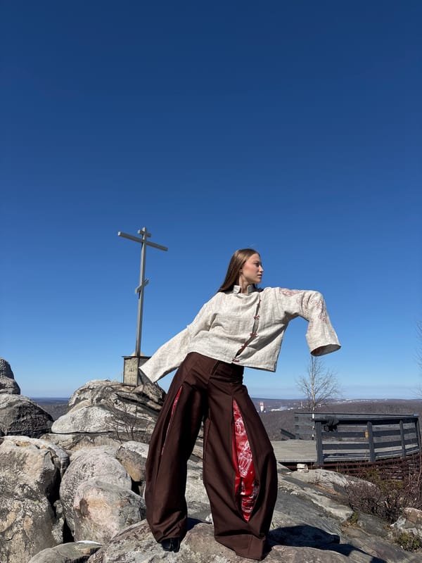 Woman poses with outstretched arms on mountain summit in Russia