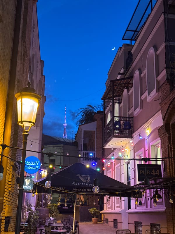 Street lamp illuminates brick building at dusk in Tbilisi