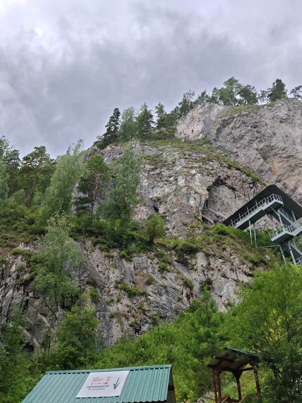Metal staircase climbs rocky cliff to cave entrance