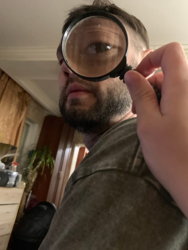 Man uses magnifying glass and mirror indoors in Zasechnyi