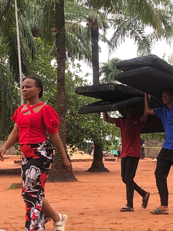 Two people carry large object in Nteje, Nigeria