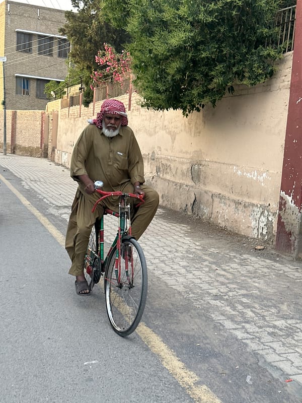 Elderly man stands on bicycle in Quetta street