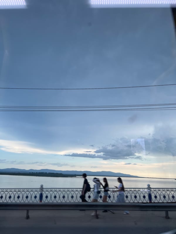 Pedestrians cross a decorative bridge in overcast Khabarovsk