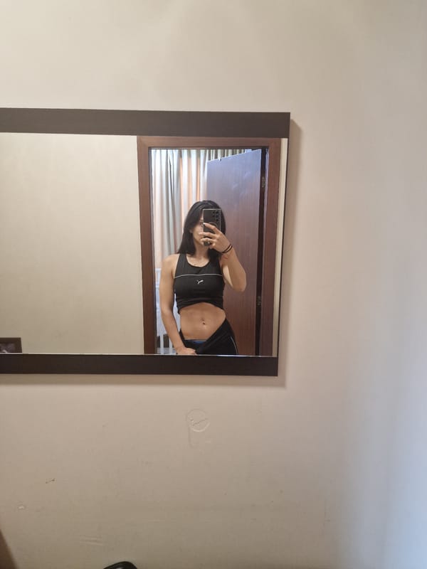 Person takes mirror selfie in light-walled room