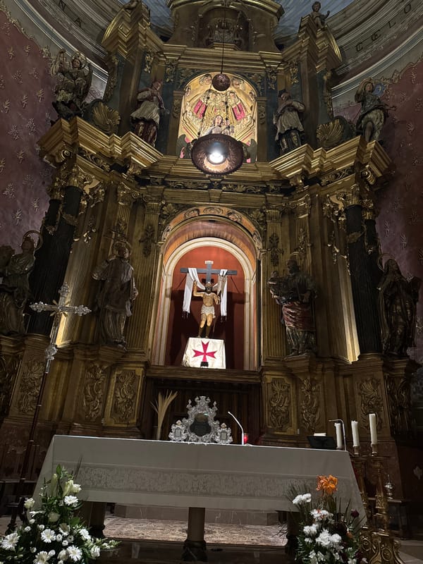 Tourist documents historic church architecture and wet streets in Pollença