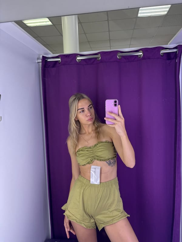 Trying on a green outfit in a Russian fitting room.