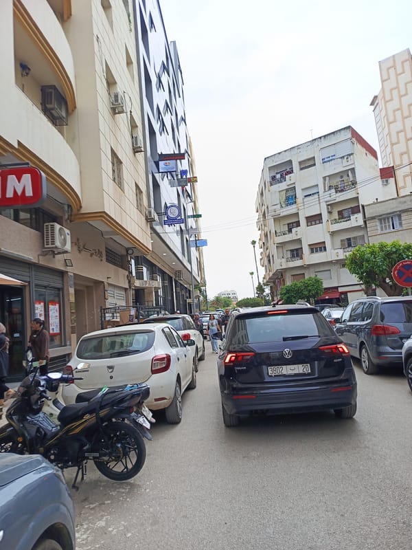 Urban street scene with moderate traffic, parked cars observed