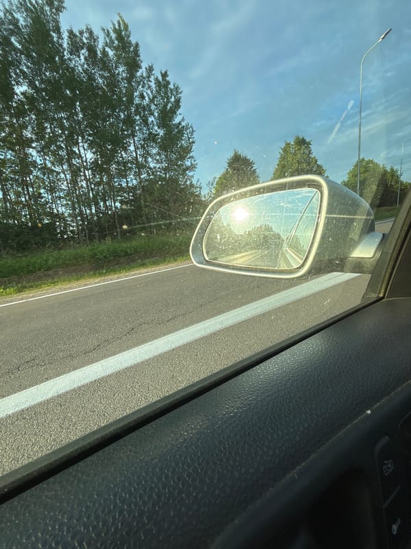 Sunset reflected in a rearview mirror on a Latvian road